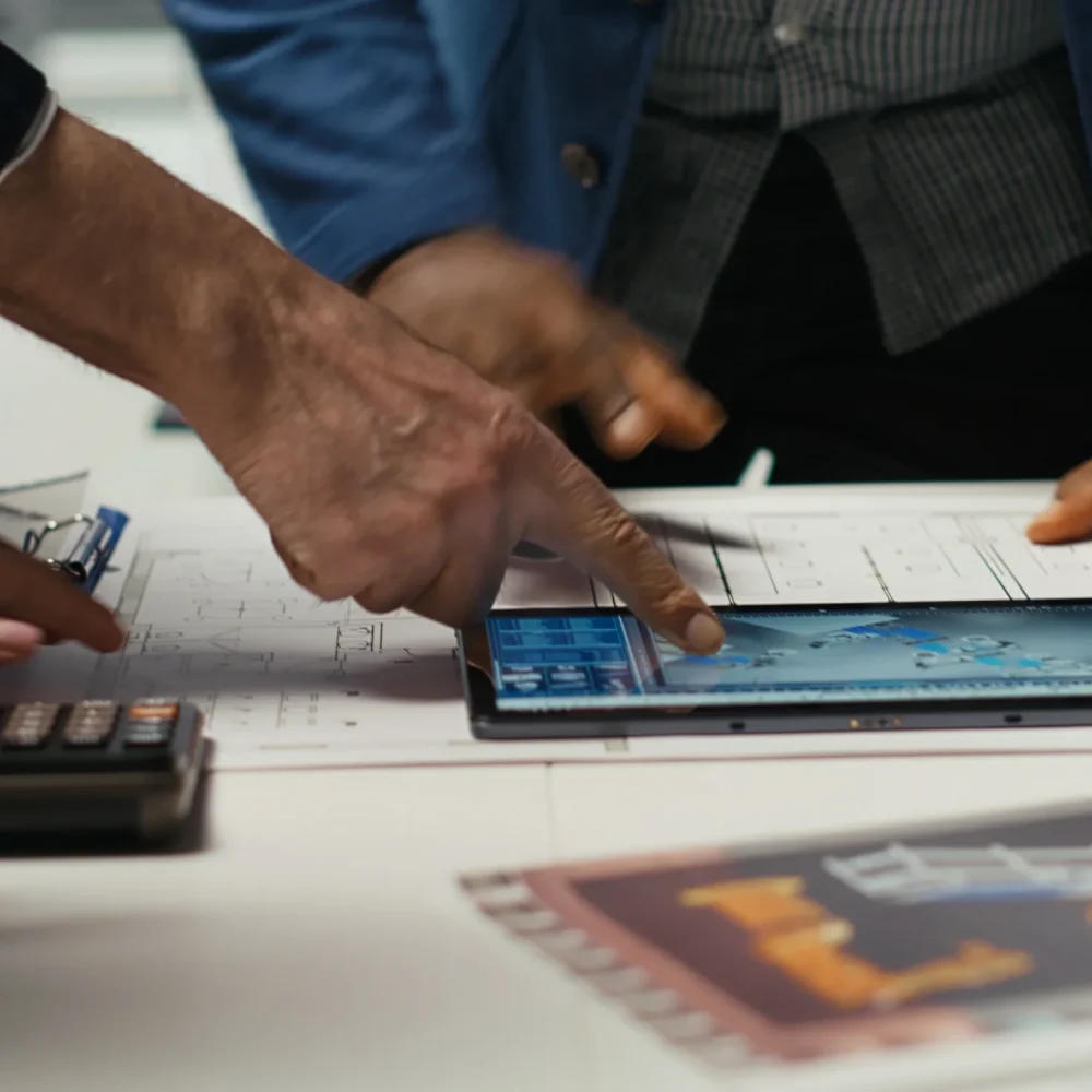 An engineering team using a tablet to analyze large-scale robotic fleet management and industrial layouts.