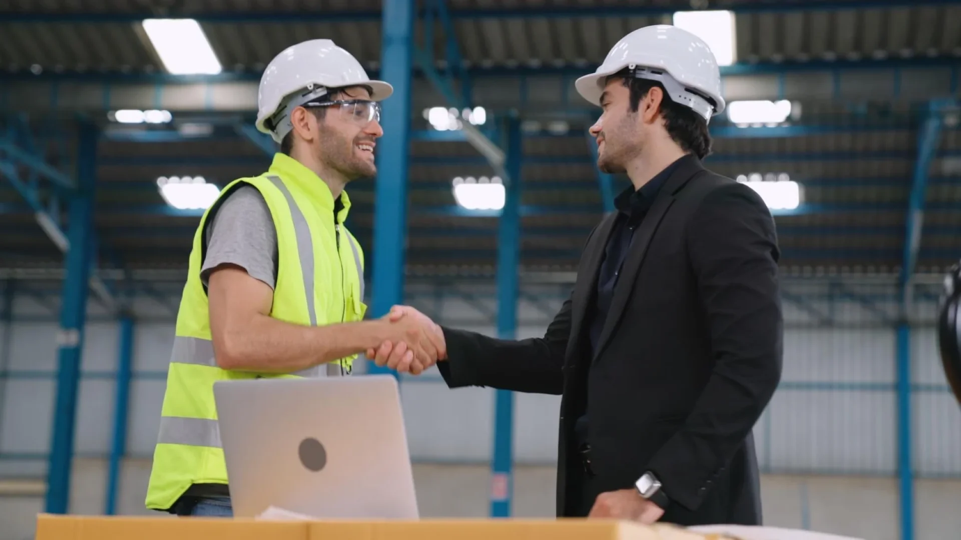 Industrial business leader shaking hands with a B2B web design agency specialist in a manufacturing facility to discuss industrial marketing and SEO.